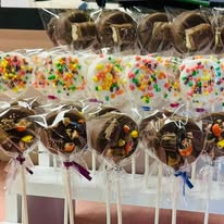 Chocolate-covered treats on sticks wrapped with sprinkles and candy bits