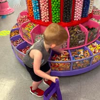 A child choosing candy from a round purple pick-and-mix display
